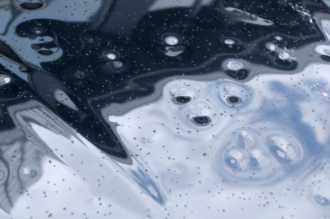 Auto Hail Damage Repair The hood of a car with dents in it from hail storm.