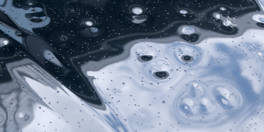 Auto Hail Damage Repair The hood of a car with dents in it from hail storm.